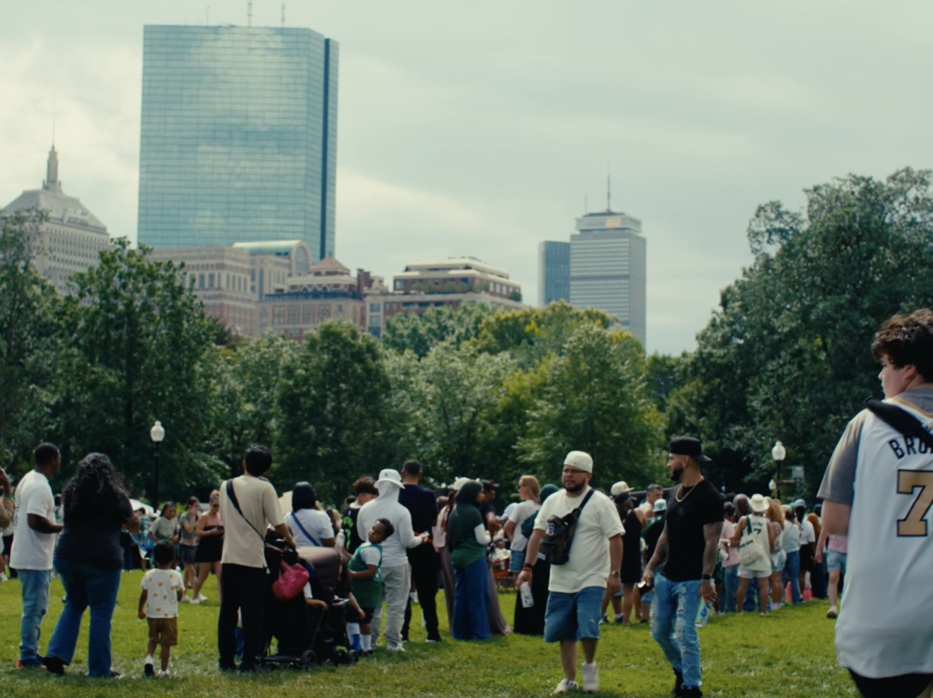 Festival crowd on Boston Common with the city skyline behind them