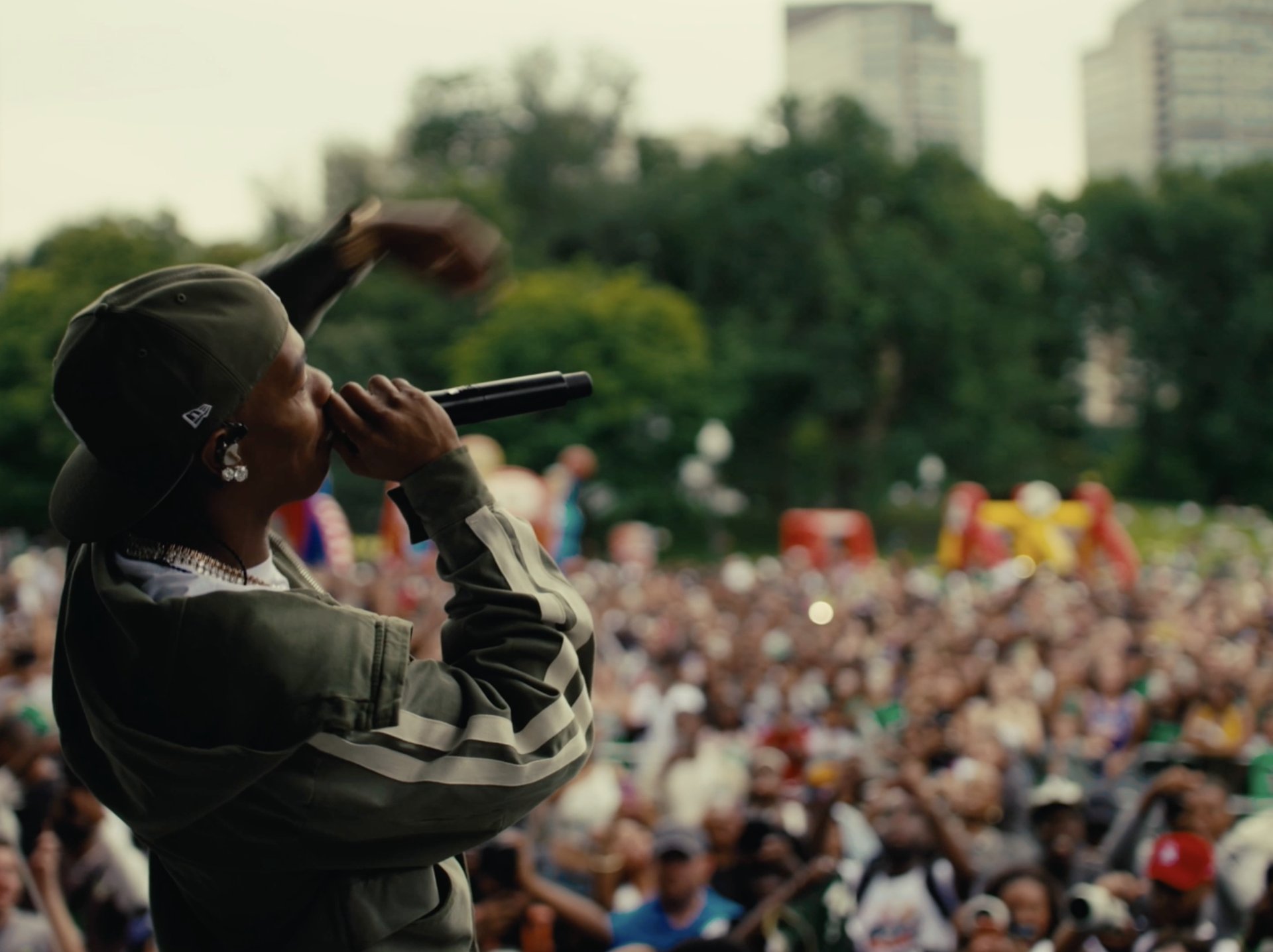 A performer on the mic silhouetted against the festival crowd