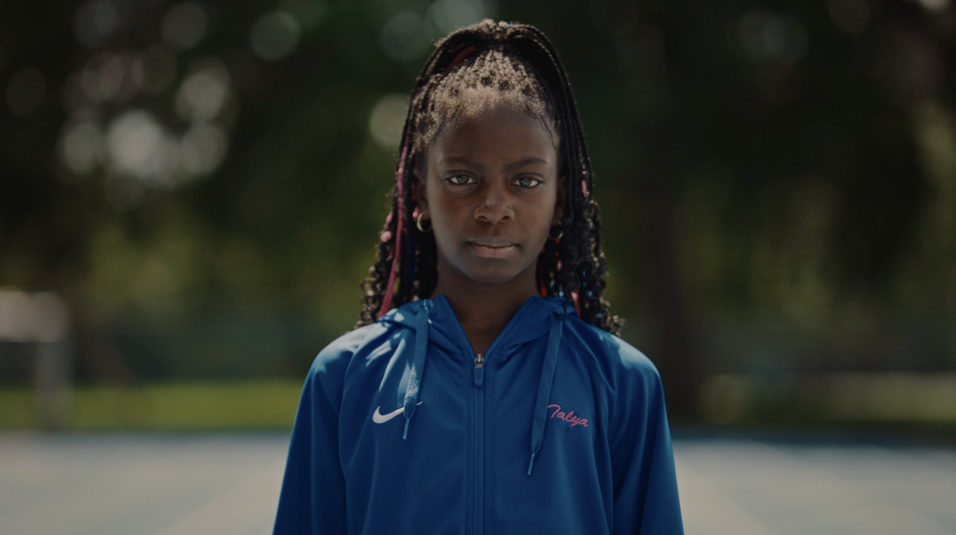 Young athlete seated on stadium bleachers, looking back at camera