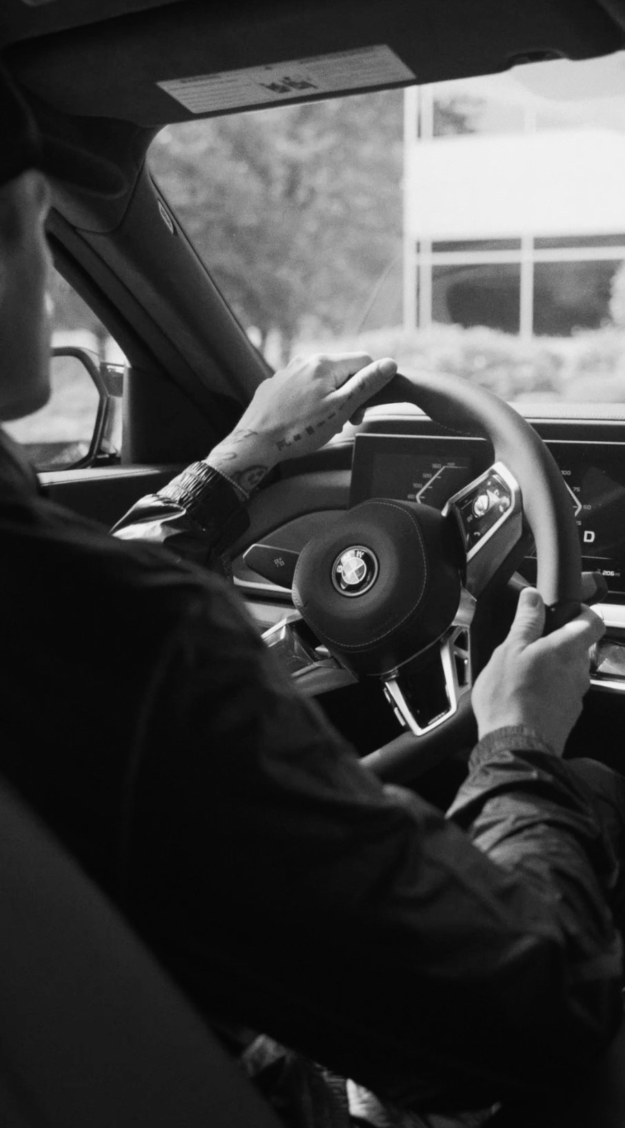 Black-and-white shot of hands on a BMW steering wheel