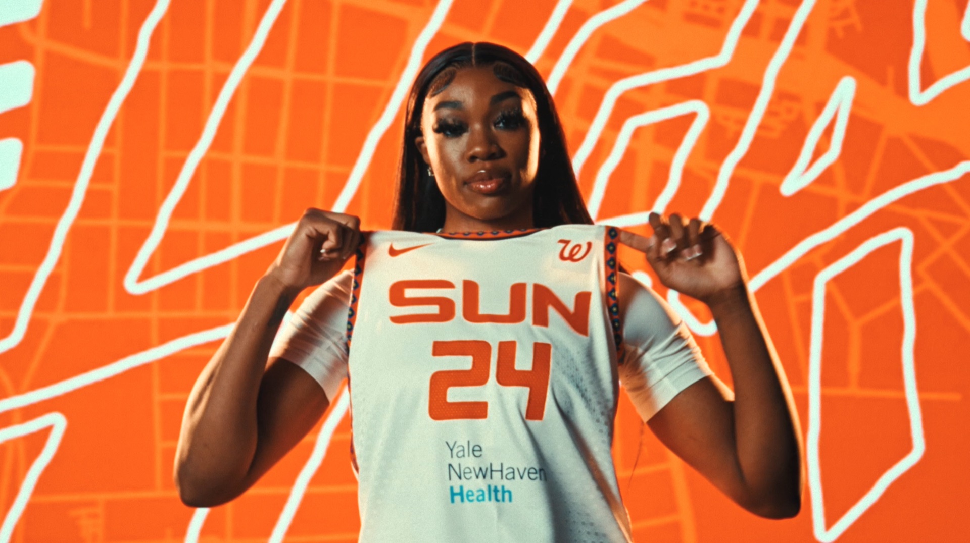 Player driving forward in a white and orange jersey against a bold graphic backdrop
