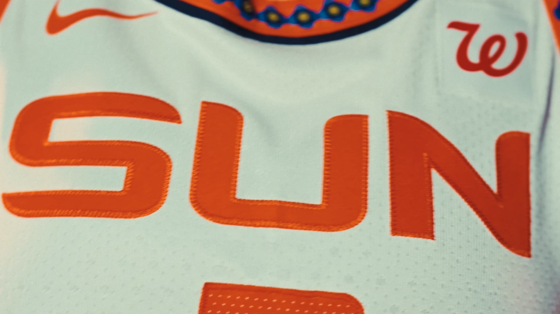 Two players in orange CONNECTICUT jerseys against a graphic city-map backdrop