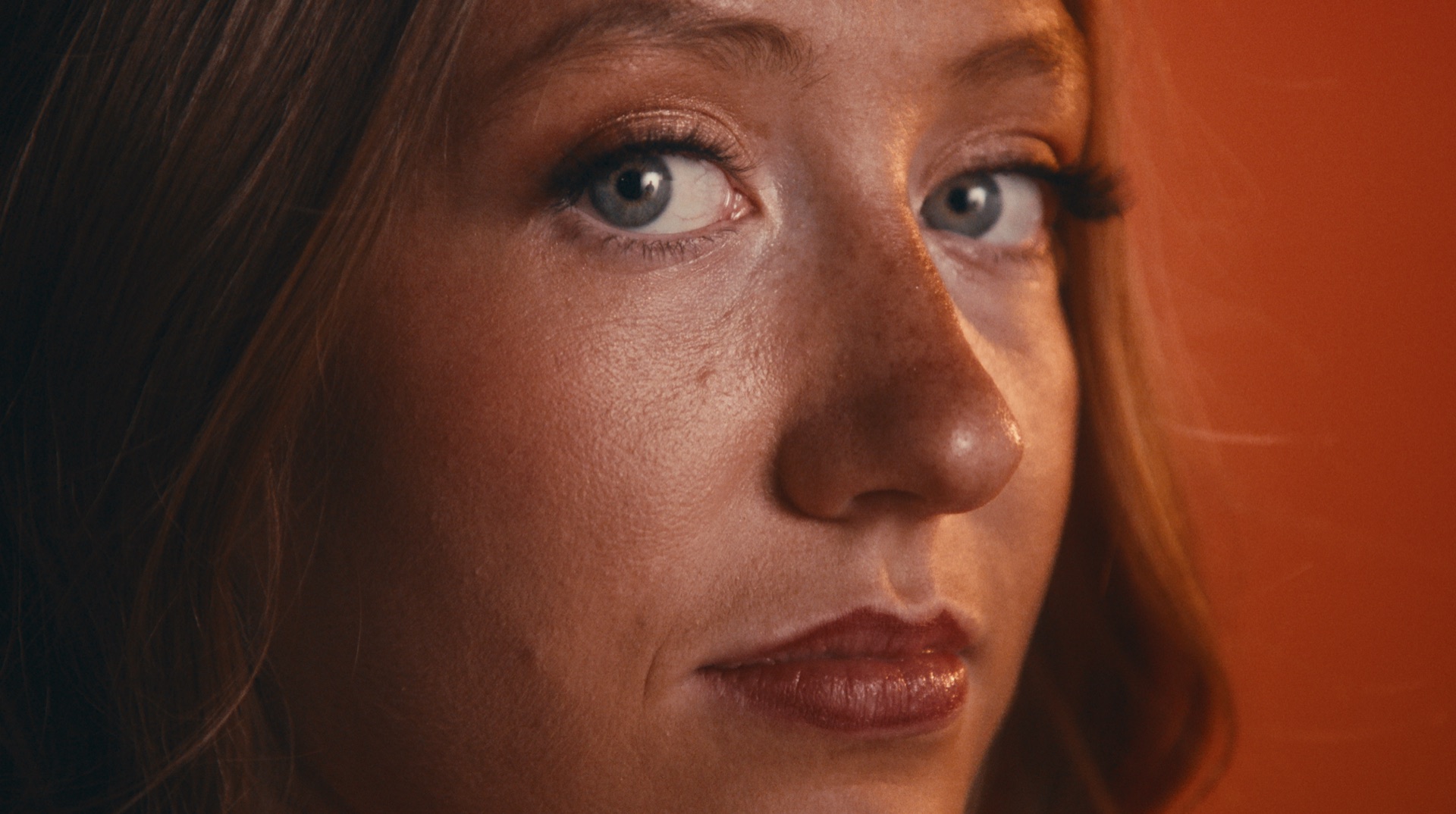 Extreme close-up portrait of a player's eyes, warm rim light along her hair