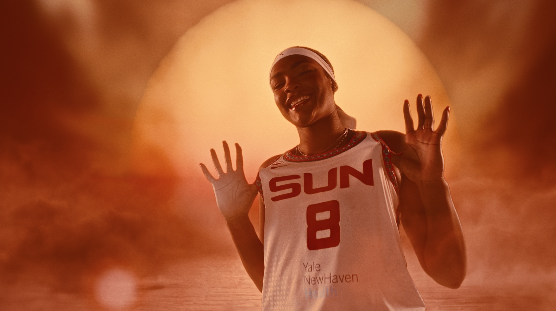 Player standing before a wall covered in Connecticut Sun archival photos, clippings, and memorabilia