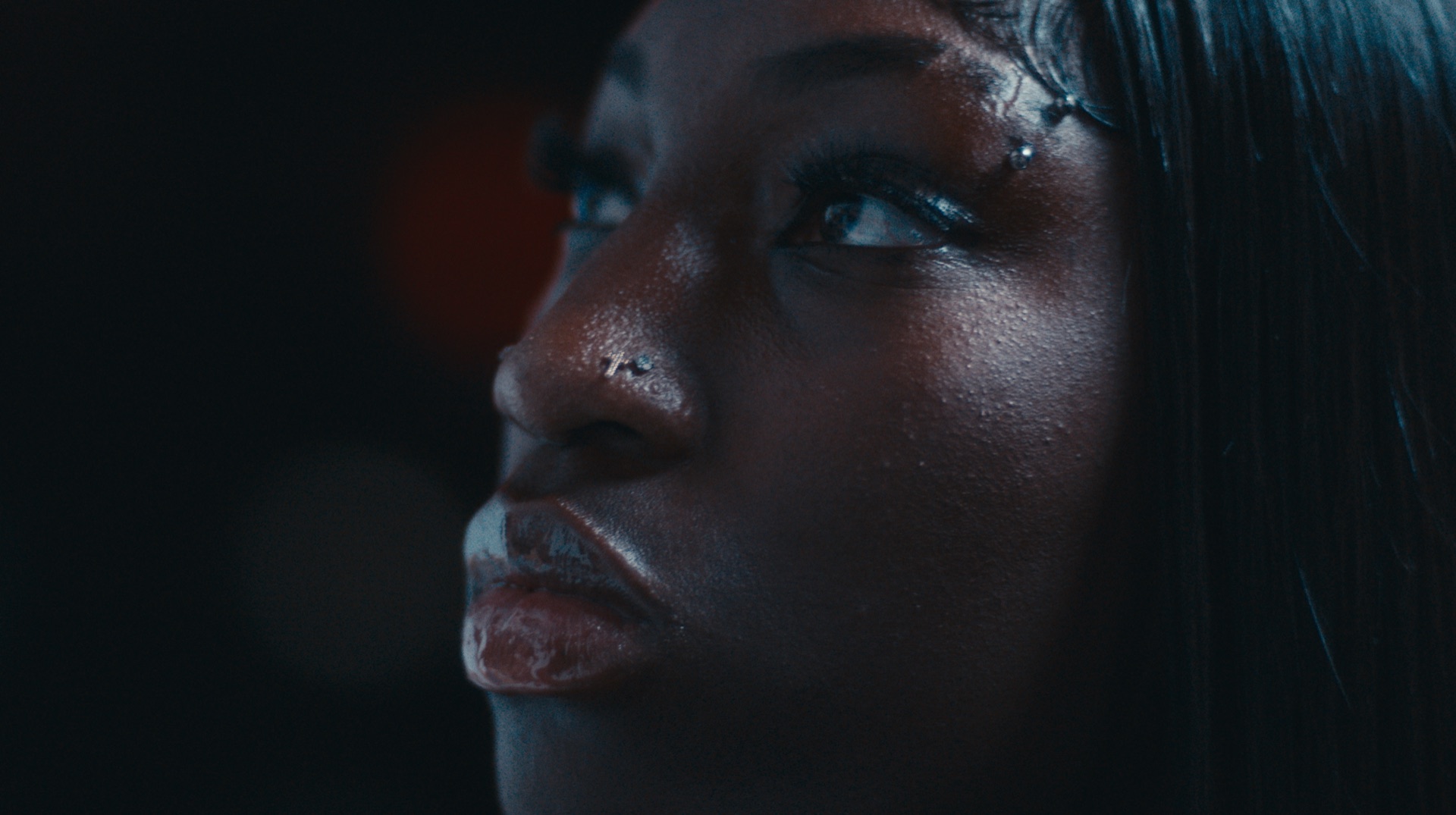 Close-up profile portrait with braided headwrap, a red light streak crossing her cheek