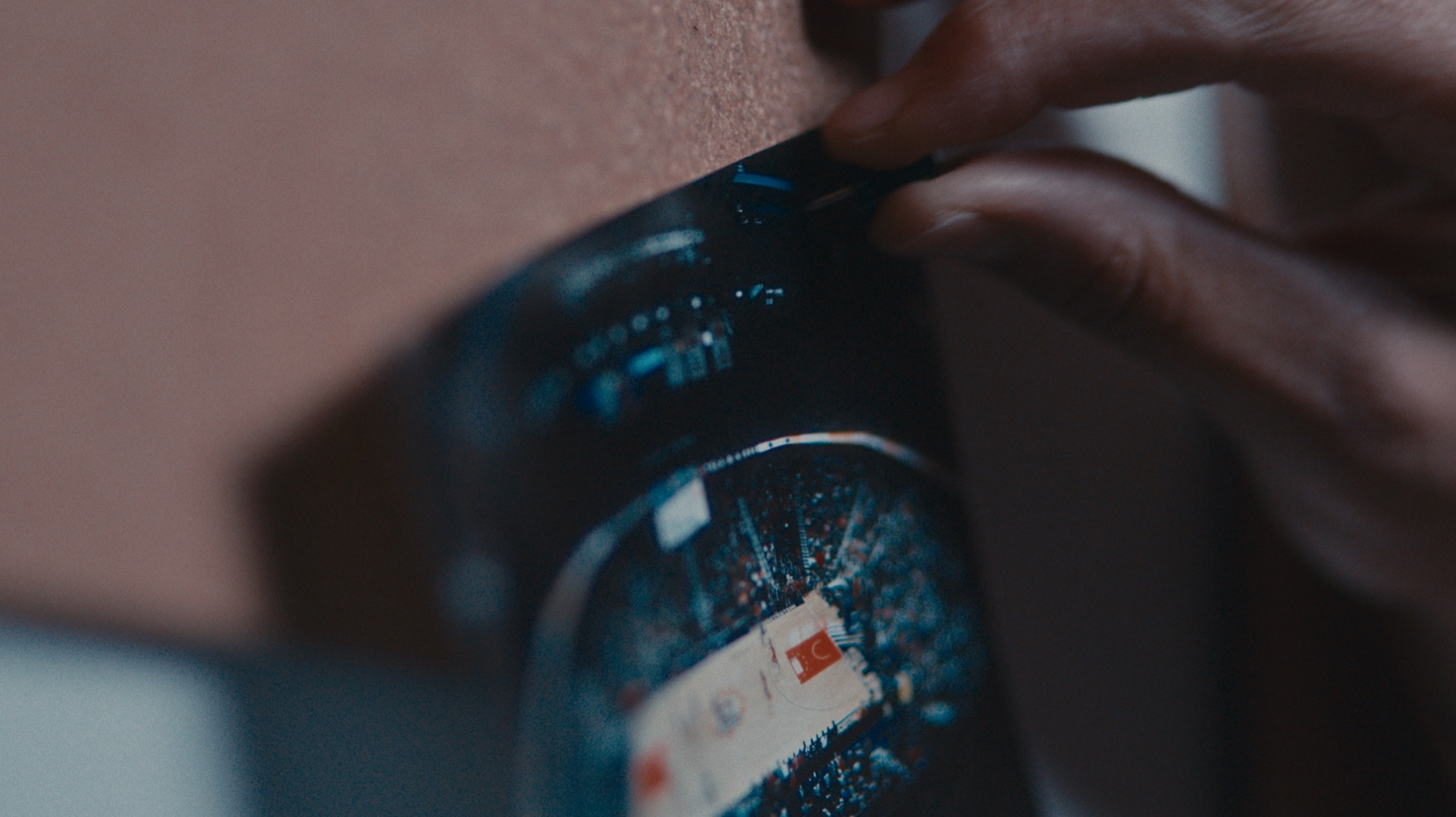 Close-up of hands pinning a curled team photo and ticket stub to a corkboard wall