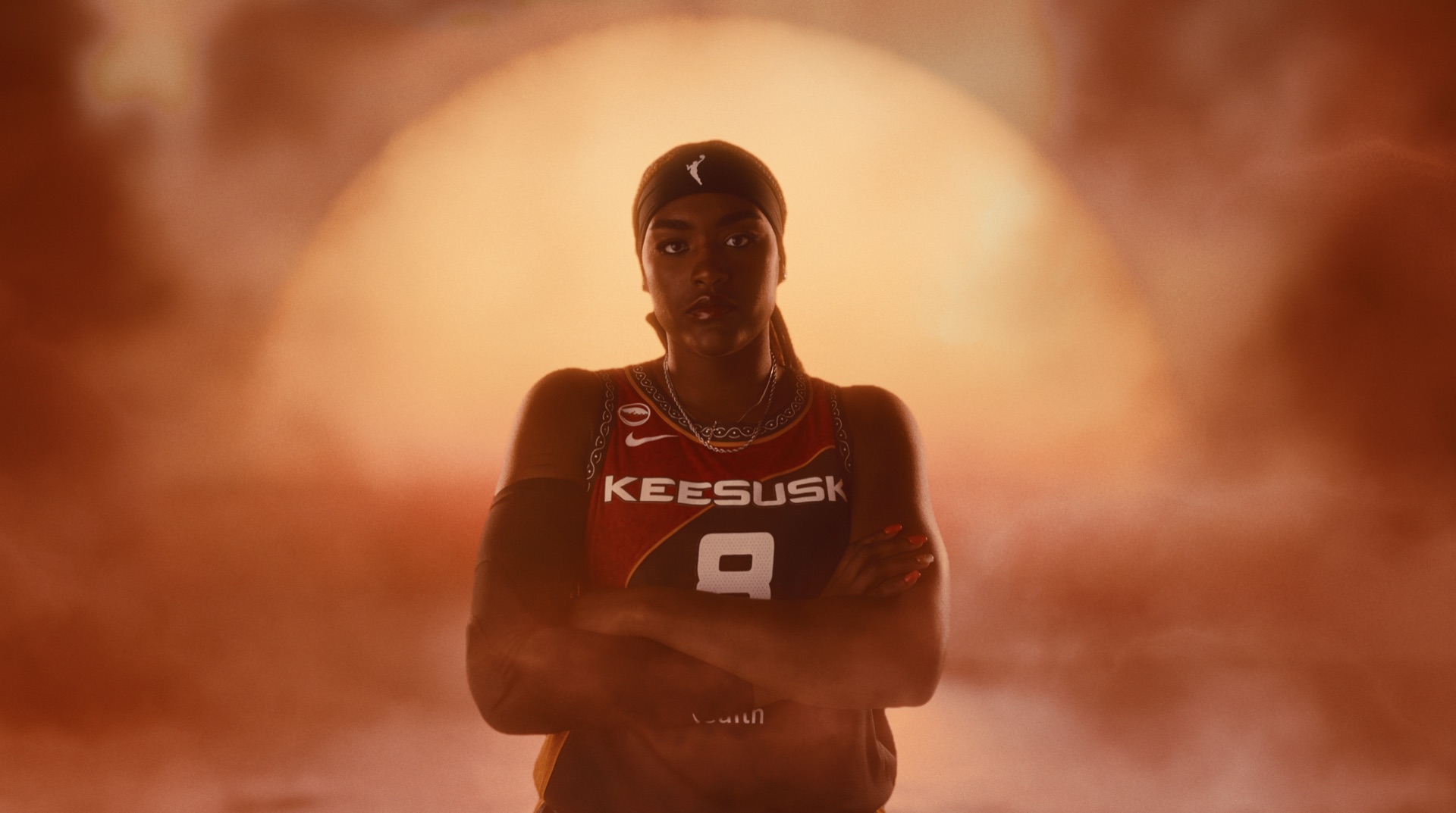 Five players in SUN jerseys standing in shallow water, silhouetted against a glowing sun through orange haze