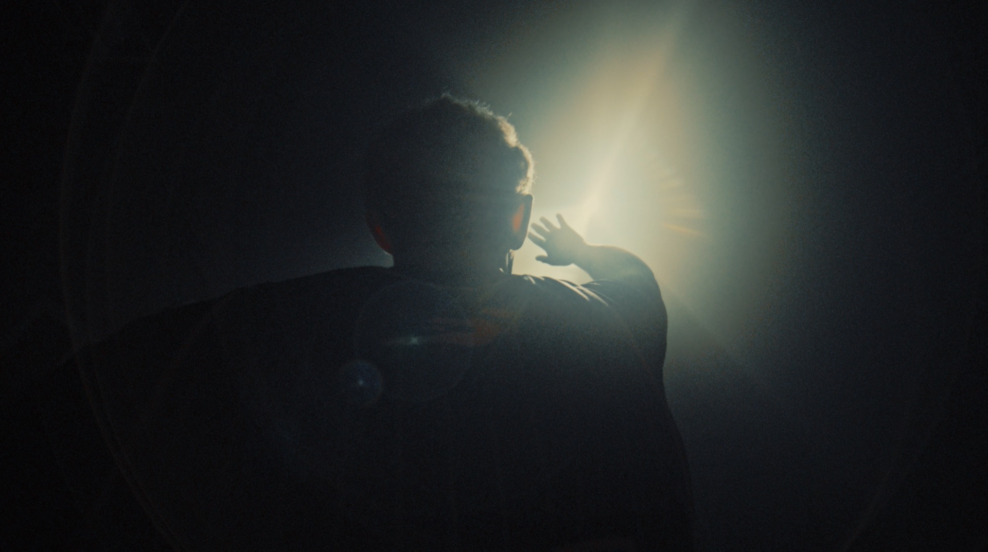 Backlit silhouette of a player reaching a hand toward bright light