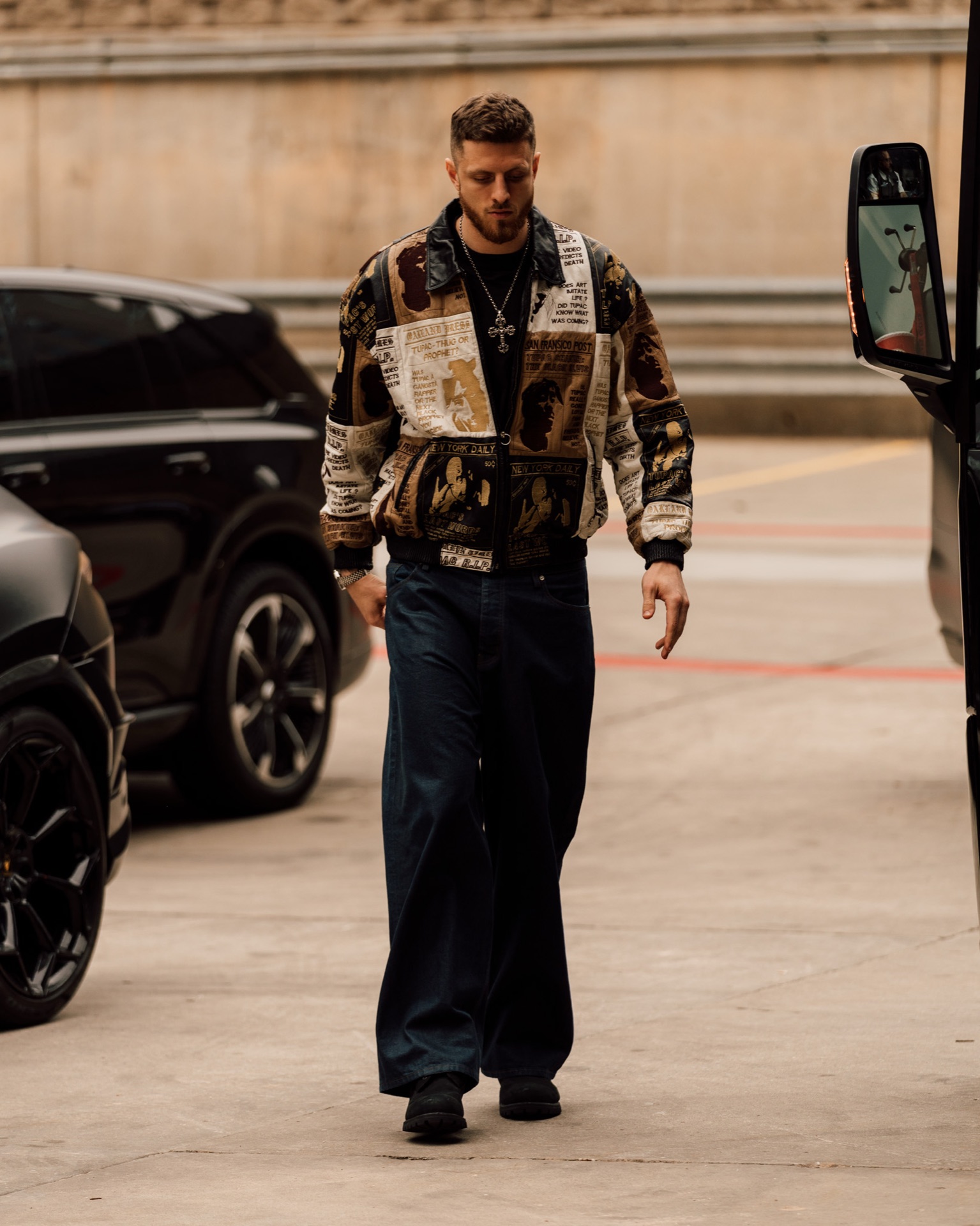 Isaiah Hartenstein walking through a parking garage in a Tupac graphic jacket and wide-leg jeans