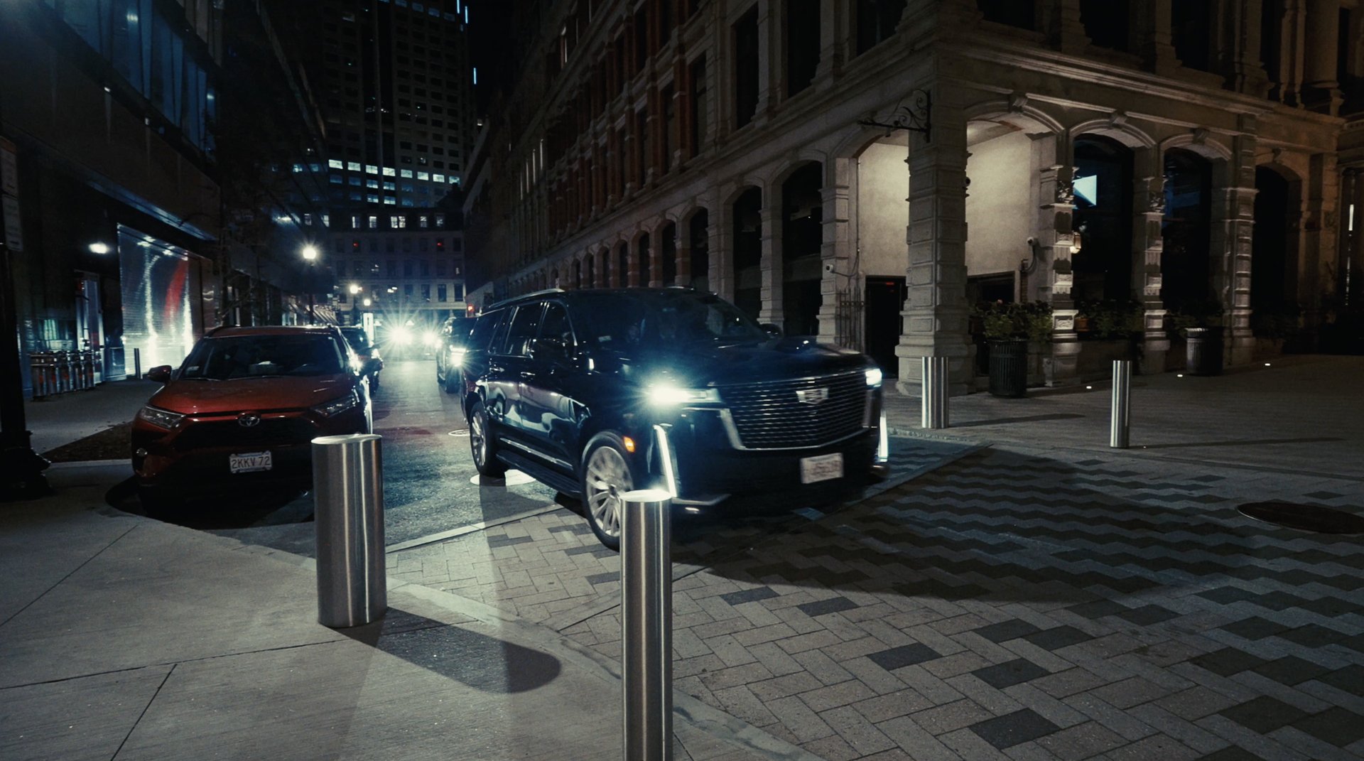 A black SUV pulling up on a city street at night