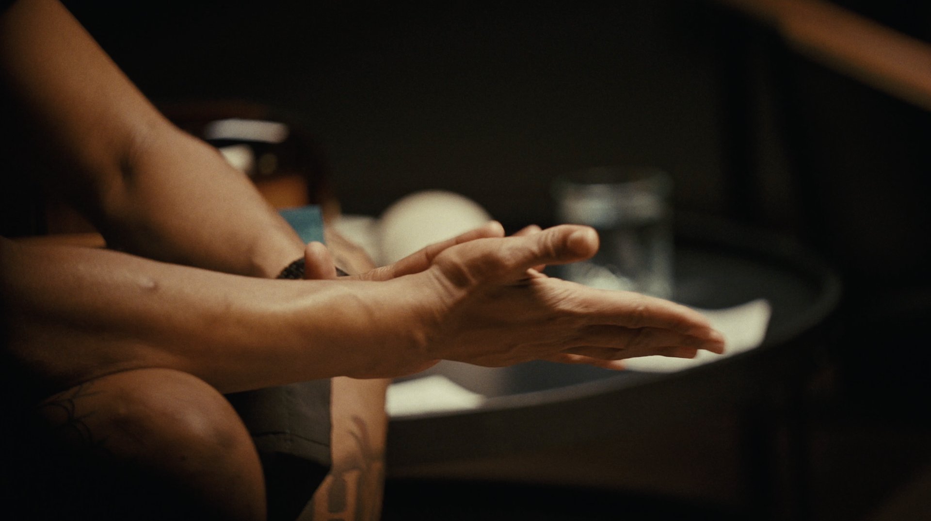 Close-up of an outstretched hand beside a glass
