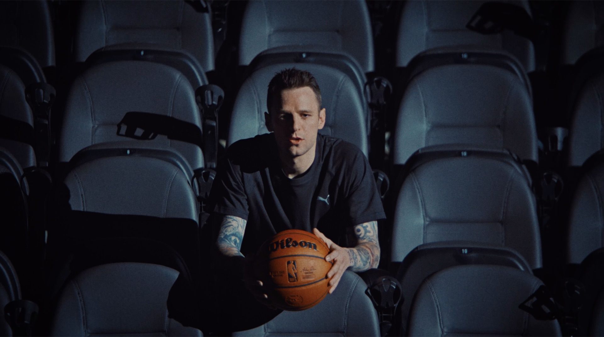 Portrait in empty arena seats holding a basketball