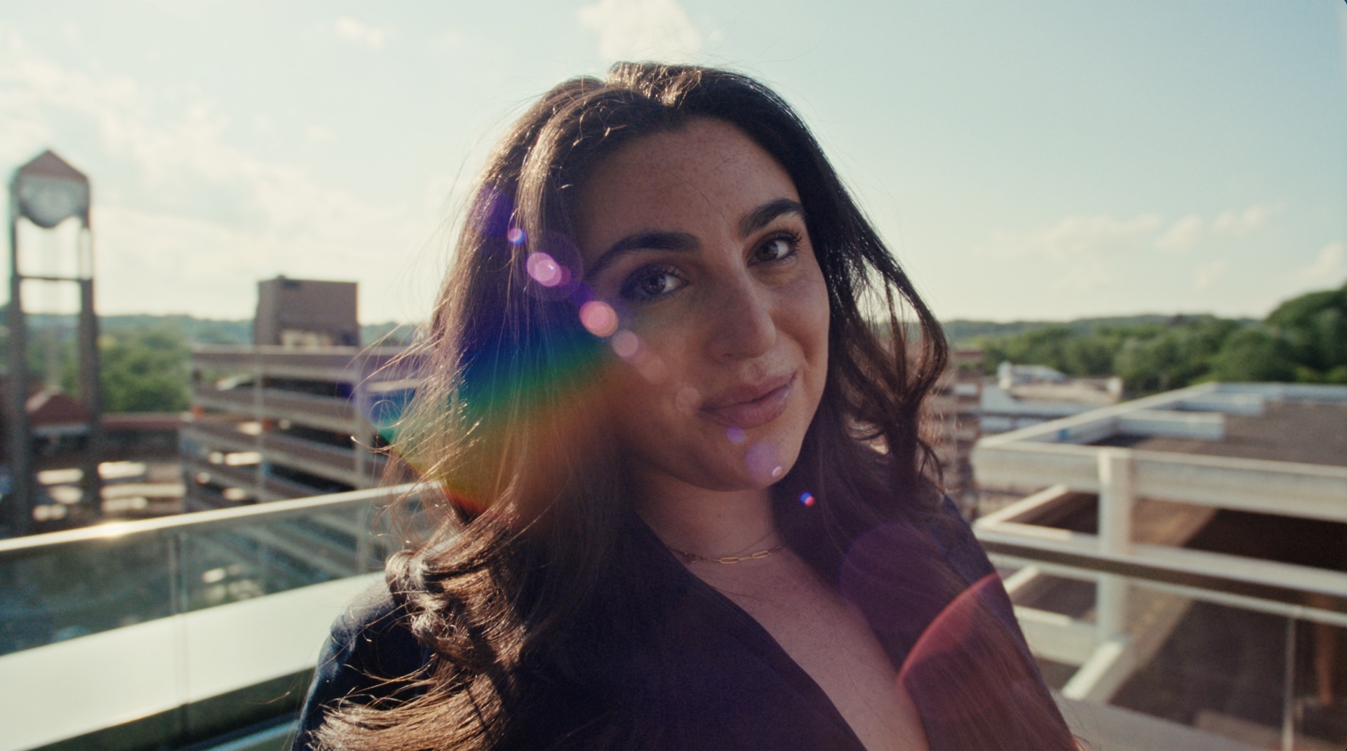 Portrait with lens flare, city skyline and water tower behind her